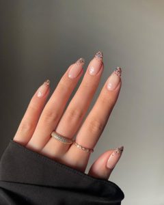 Nude nails with colorful glitter faded on tips. 