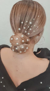 Low, blonde bun with pearls in hair. 